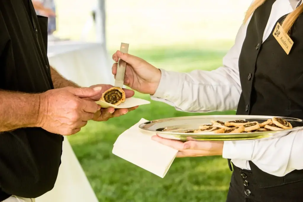 Eine Mitarbeiterin serviert Gäste. Unser Service: Cateringmanagement Düsseldorf