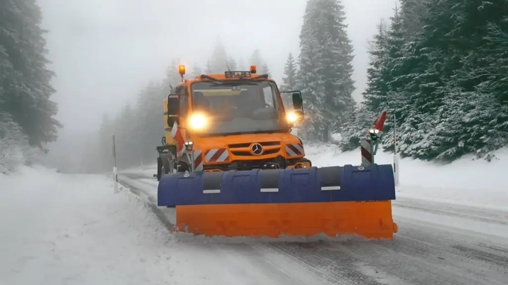winterdienst in Düsseldorf , Dortmund und NRW, orangefarbener Unimog räumt Schnee von der Straße
