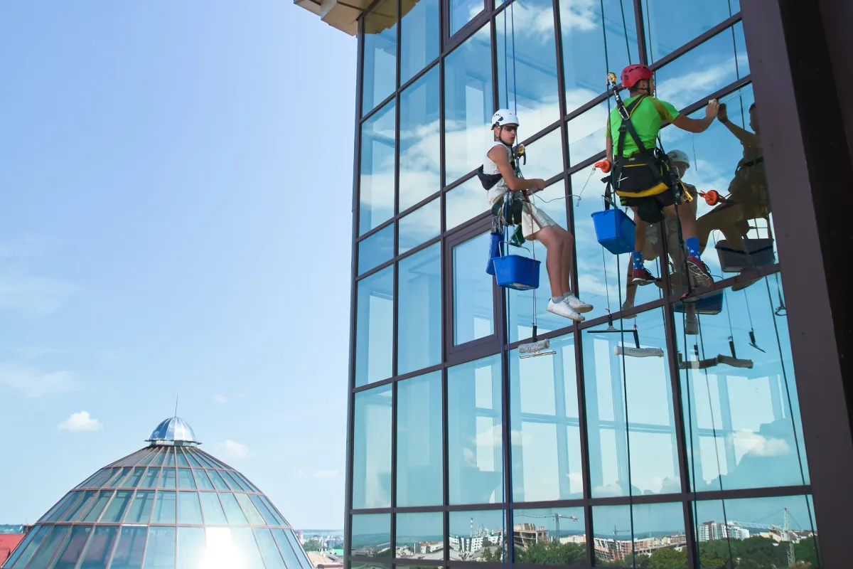 Zwei Mitarbeitern reinigen Fenster. Das ist unser Service: Gebäudereinigung Düsseldorf - Fensterreinigung